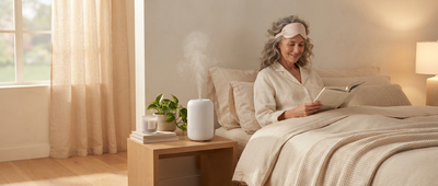 Femme lisant au lit avec masque de sommeil, humidificateur diffusant une brume douce